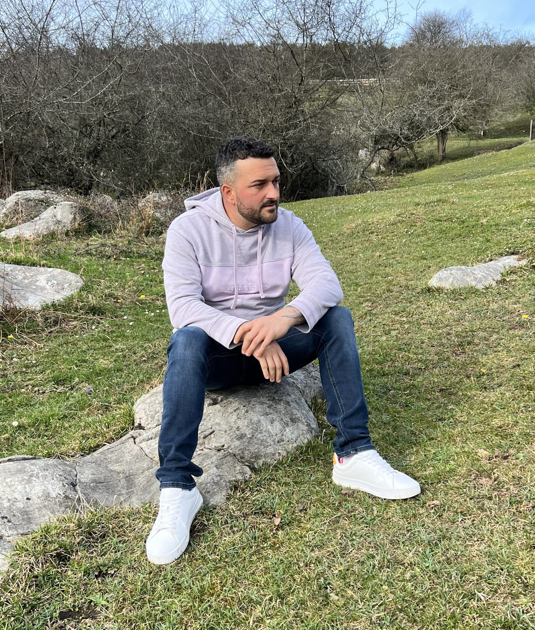 Cristian Nieto sentado en una roca en el campo